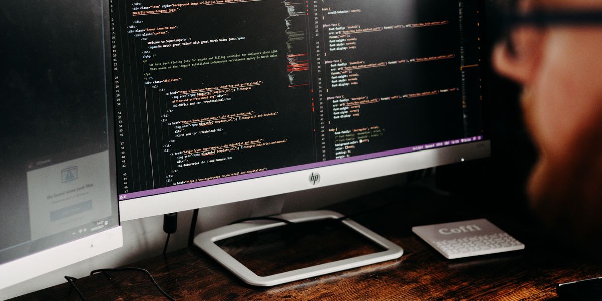 デュアルモニターでコードを確認しながら作業するエンジニア