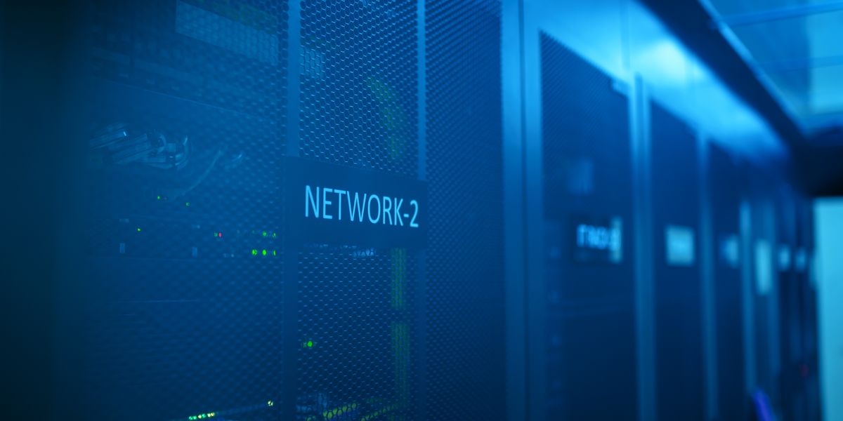 青い照明のサーバールームに並ぶネットワーク機器のラック
